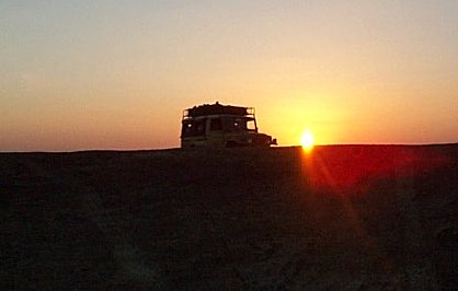 Jeep bij zonsondergang in de woestijn